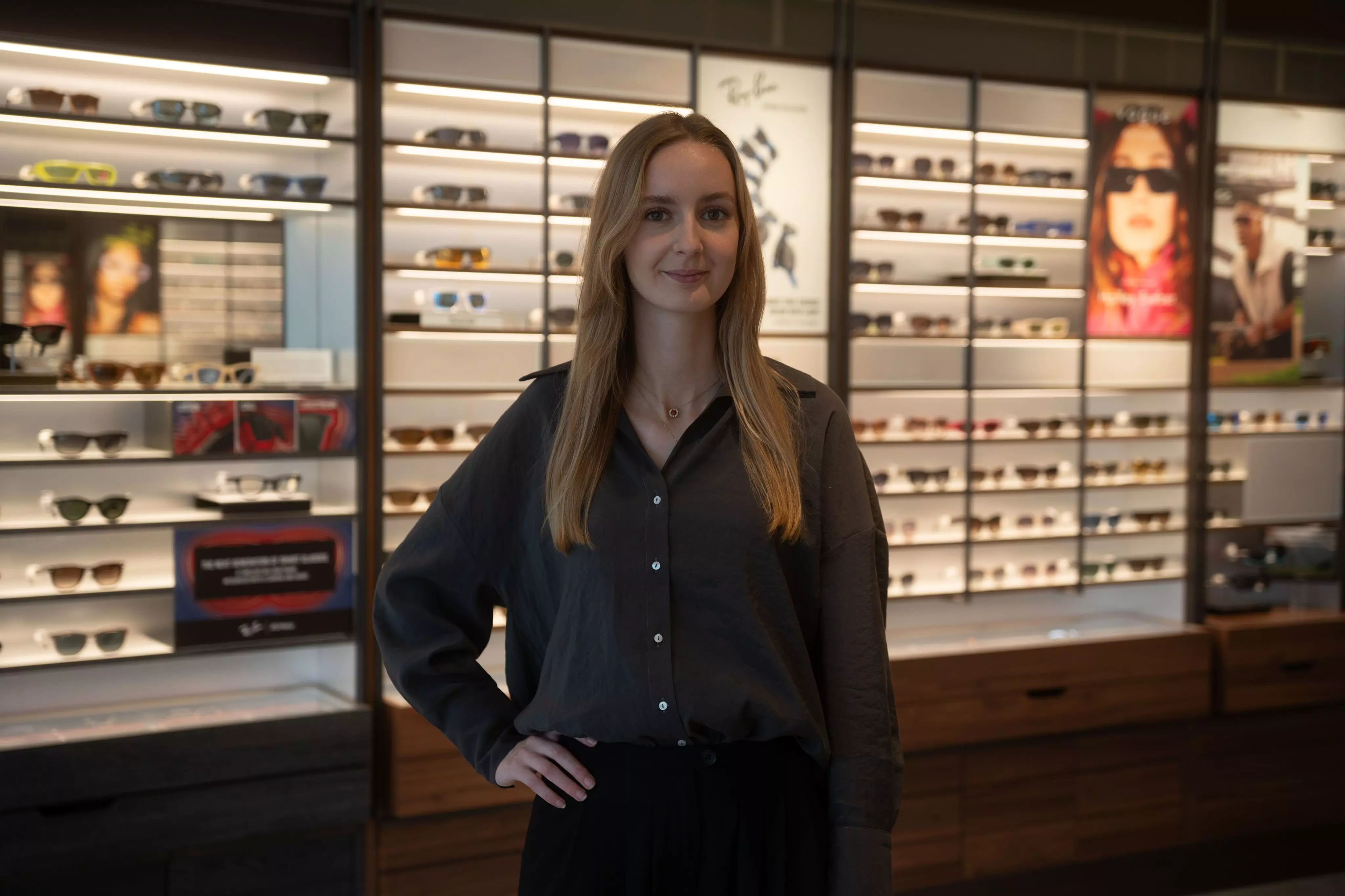 Opticien in opleiding poseert voor een brillenewand