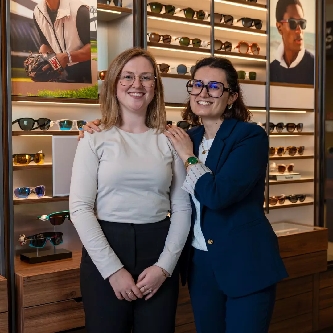 Medewerkers van Pearle staan samen voor een brillenwand