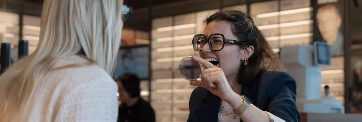 Zelfstandig zaakvoerder Nareen laat klant een  montuur passen en het effect van meekleurende  glazen zien terwijl ze samen lachen